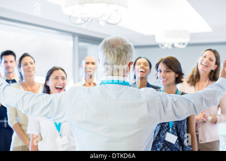 Businessman greeting enthusiastic colleagues in office Stock Photo