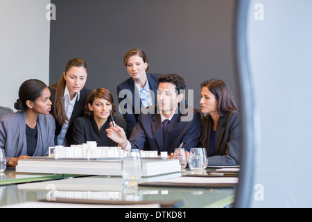 Business people examining model in meeting Stock Photo