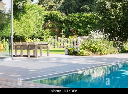 Table and chairs by outdoor swimming pool Stock Photo