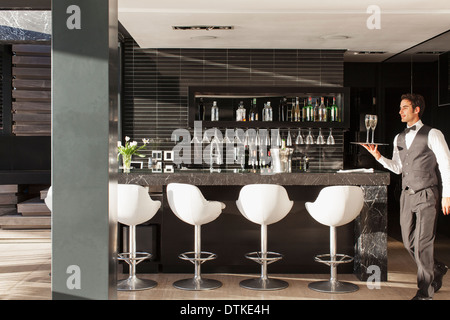 Waiter carrying tray of glasses in bar Stock Photo