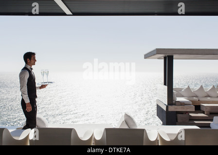 Waiter serving champagne at cabana overlooking ocean Stock Photo