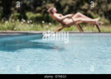 Woman sunbathing by swimming pool Stock Photo