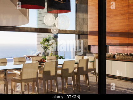 Table and chairs in modern dining room overlooking ocean Stock Photo