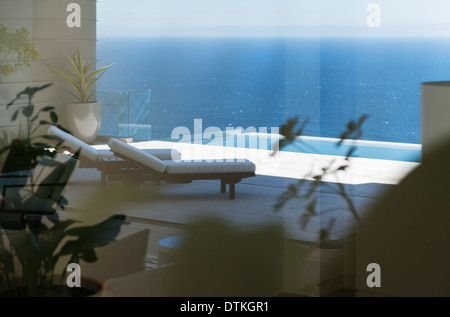 Lounge chairs and infinity pool overlooking ocean Stock Photo