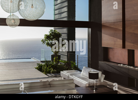 Sofas and tables in modern living room overlooking ocean Stock Photo