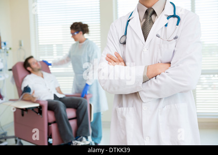 Doctor Standing Arms Crossed In Chemo Room Stock Photo