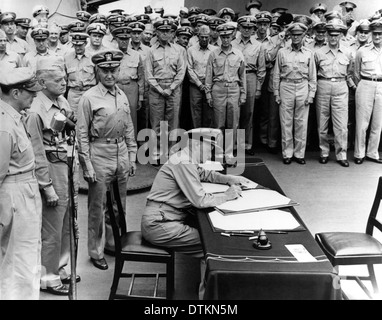 US Navy Fleet Admiral Chester W. Nimitz signs the Instrument of Surrender as US Represenative during formal surrender ceremonies on the USS MISSOURI September 2, 1945 in Tokyo, Japan. Standing directly behind him are (left-to-right): General of the Army Douglas MacArthur; Admiral William F. Halsey, USN, and Rear Admiral Forrest Sherman. Stock Photo