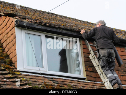 Roofer workman repairing storm damage to a tiled roof tools Stock Photo