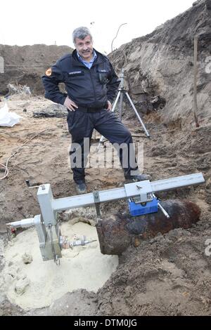 Hamburg, Germany. 20th Feb, 2014. Head of the bomb disposal team of the Hamburg fire service Peter Bode stands next to a British 500-pound-bomb in Hamburg, Germany, 20 February 2014. A bomb was discovered during excavation work and was defused successfully. Photo: Bodo Marks/dpa/Alamy Live News Stock Photo