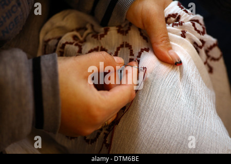 Color shot of two hands holding a needle and sewing  Stock Photo