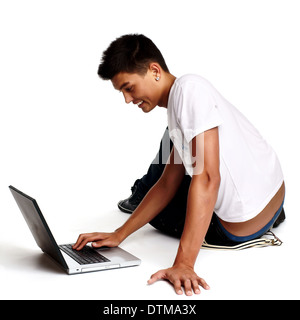 Pensive young man sitting on floor using laptop, isolated on white  Stock Photo