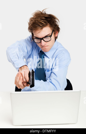 Young man in the office and pointing a gun to the laptop Stock Photo