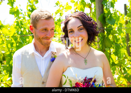 Bride and groom sharing a moment and posing for the camera in this portrait of the two people in a vineyard at a winery on their Stock Photo