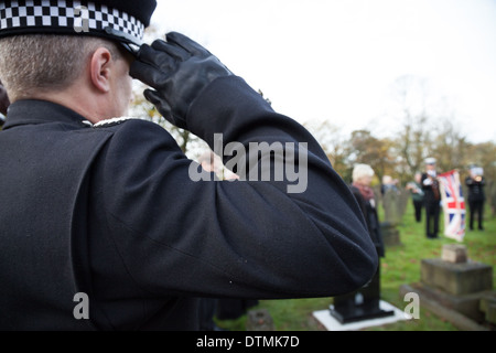 A Police officer salutes during the dedication to PC James Gordon in St Helens. PC Gordon was murdered on duty in 1893. Stock Photo