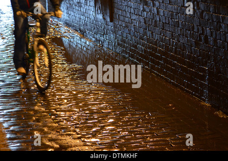 Cyclist speeding through the canal underpass, on the old cobbles Stock Photo