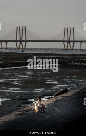 Low tide view of the Bandra Worli Sea Link bridge from the Worli Mahim side. This man waits alone for the sun to set. Stock Photo