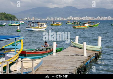 Brazil, Santa Catarina, Porto Belo. Colorful local fishing boats with city skyline in distance. Stock Photo