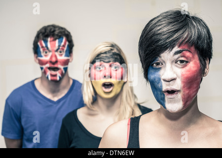 Group of surprised happy people with painted flags on their faces. Stock Photo