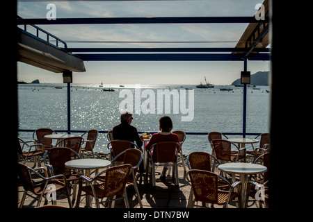 A couple enjoy the sea views from a cafe in the seaside town of Cadaques, Cap de Creus peninsula, Costa Brava, Catalonia, Spain Stock Photo