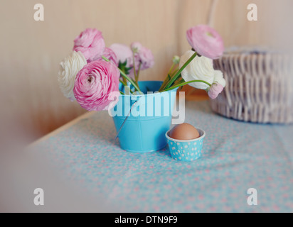 beautiful and delicate bouquet of buttercups in a blue bucket and egg in a basket Stock Photo