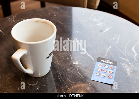 Full card. Caffe Nero loyalty card with all stamps filled in for a free cup, next to an empty mug of coffee Stock Photo