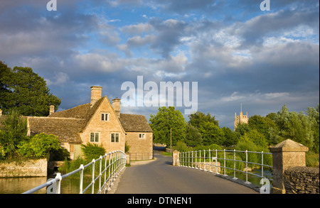 Evening sunlight glows on the old mill and church in the Cotswolds village of Fairford, Gloucestershire, England. Stock Photo