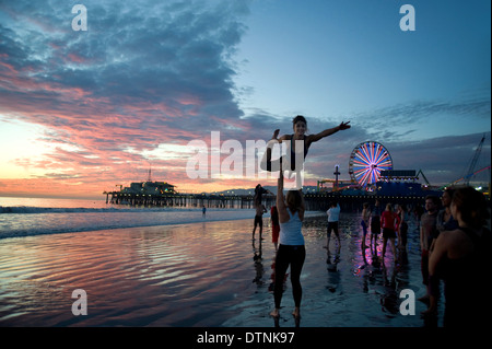 Young people practicing gymnastics near the Santa Monica Pier at sunset Stock Photo