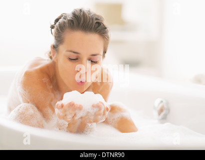 Young woman playing with foam in bathtub Stock Photo
