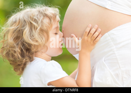 Child kissing belly of pregnant woman Stock Photo