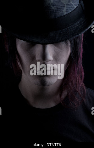 A gothic man wearing a Fedora hat, a moody headshot with black background Stock Photo