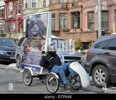 A man on a four wheeled bicycle advertising for a charity auction in Crown Heights Brooklyn, New York Stock Photo