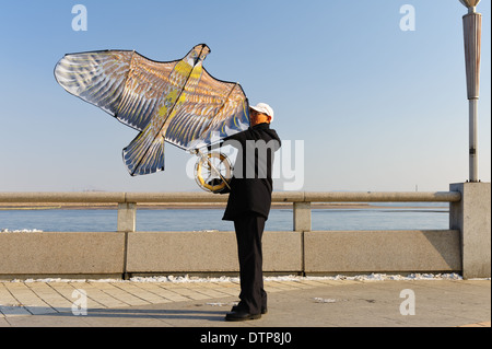 Man lifting his kite, waiting for wind. Dandong,  Liaoning province. China Stock Photo