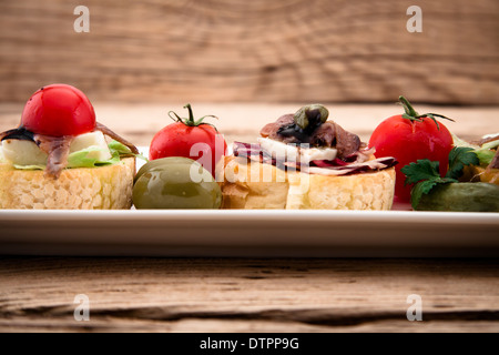 Crostini with mozzarella cheese anchovy and tomato on wooden board Stock Photo