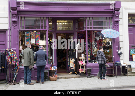 People looking into an antique and curio shop with elegant clothing on dressmakers dummies Stock Photo