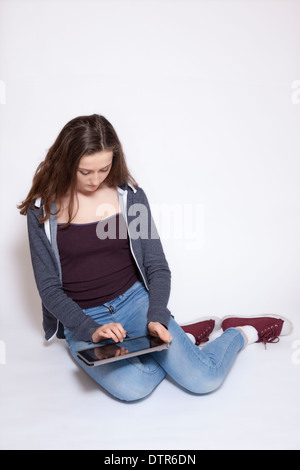 Young female sitting using digital tablet, isolated on white background. Stock Photo