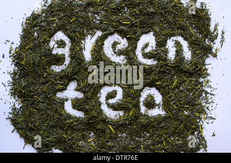 The words green tea shown among green tea leaves. Stock Photo