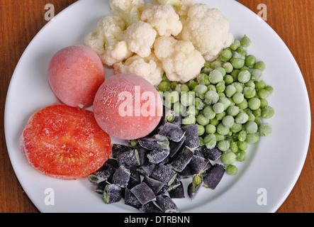 heap of frozen black currant covered with hoarfrost in the white plate on the wooden surface Stock Photo