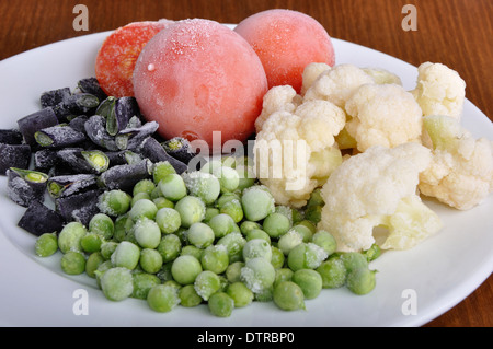 heap of frozen black currant covered with hoarfrost in the white plate on the wooden surface Stock Photo