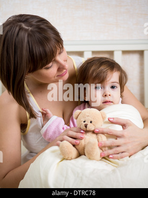 mother looking at kid in bed Stock Photo