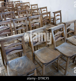 Sitting uncomfortably: rows of hard wooden seats lined up in a church. Stock Photo