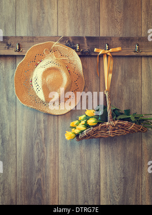 Straw hat with freshly picked roses hanging on shed door - vintage tone effect Stock Photo