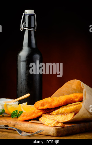 Traditional fish and chips wrapped in paper with beer bottle Stock Photo