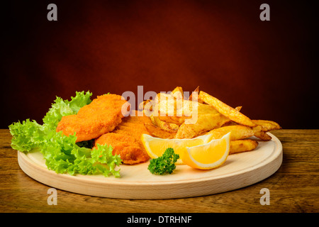 still life with traditional fish and chips, lemons, on a wooden plate Stock Photo