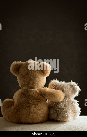 Two teddy bears sitting side by side on couch Stock Photo
