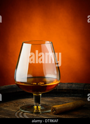 still life with glass of cognac and cigar on a wooden barrel Stock Photo