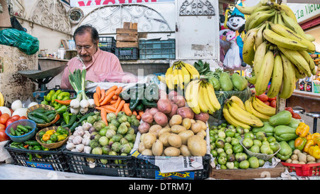 vegetable vendor in stall at mercado La Merced market with neatly arranged display of unblemished fresh produce & bananas Oaxaca Stock Photo