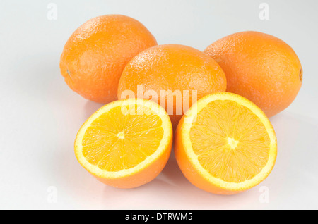Whole oranges, with one cut open on white background. Stock Photo