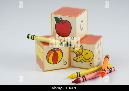 Educational plastic preschool blocks with ABC's and picture of apple,ball,cat. Crayons of red,yellow,orange and green. Stock Photo
