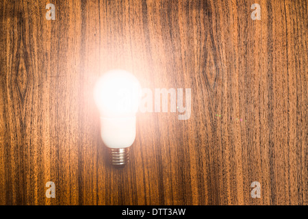Illuminated eco friendly light bulb on wooden background. Conceptual image of ideas, invention and success with copy space. Stock Photo