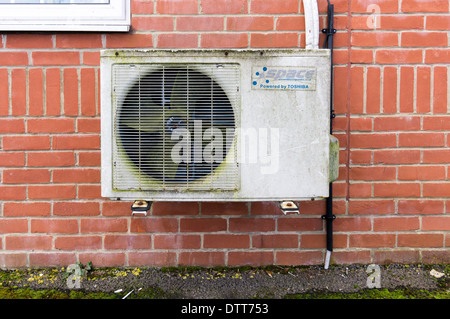 Old air conditioning unit and fan on brick wall Stock Photo